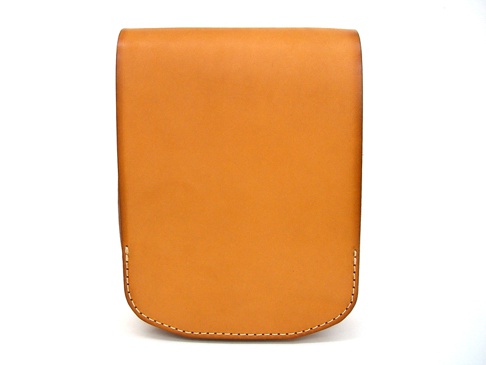 棕褐色皮革翻蓋直式單肩包，簡約設計，邊緣有縫線裝飾，呈現職人手作質感。