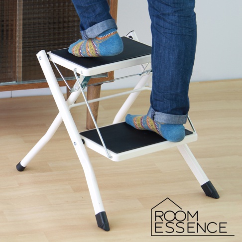 白色金屬摺疊樓梯椅，配備黑色防滑踏板，展示架上有人穿著彩色襪子站立。