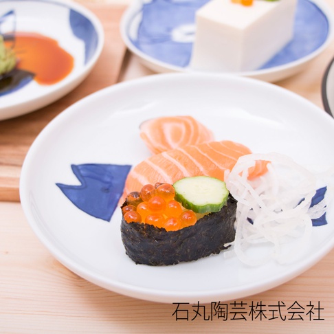 白色陶瓷小碟，印有藍色魚形圖案，上面盛有鮭魚生魚片、鮭魚卵軍艦壽司及醃漬蘿蔔絲。