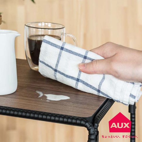 BOW 廚房工業風單層置物架，木紋桌面，黑色鐵管邊框，桌面上有咖啡杯、白色水壺及藍白格紋抹布，桌面上有少量白色液體。