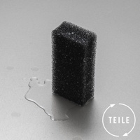 一塊黑色超細纖維海綿，具有細密的網狀紋理，放在淺灰色背景上，周圍散落著水滴。海綿底部邊緣有白色水漬。右下角有一個白色圓形箭頭標誌，其中包含文字「TEILE」。