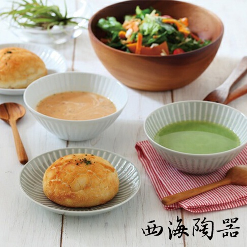 一套波佐見燒的 FUWARI 四件式碗盤，包含兩個白色有條紋的碗，分別盛著橘色濃湯和綠色飲品，以及兩個灰色有條紋的盤子，各放著一個麵包。