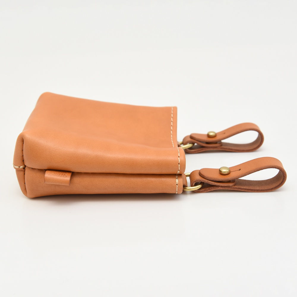 職人手作皮革多用途工作用腰袋 E-27，採用淺棕色皮革製成，側面有兩個皮革提把，以黃銅鉚釘固定，縫線清晰。