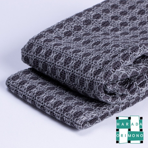 深灰色網格紋理的備長炭沐浴巾，材質柔軟，織法細緻，兩條沐浴巾堆疊擺放。