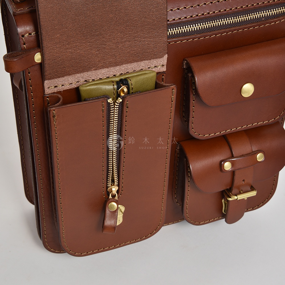 職人手作三用後背包，棕色皮革材質，設有三個外部口袋，其中一個為拉鍊開合，並有銅質釦件和拉鍊。