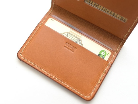 職人手作皮革雙折證件夾，呈現自然色澤的皮革材質，縫線清晰，內有卡片插槽，可收納證件。