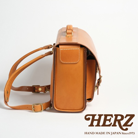 職人手作皮革橫式書包，焦糖色牛皮材質，側邊視角，展示精緻車縫細節。