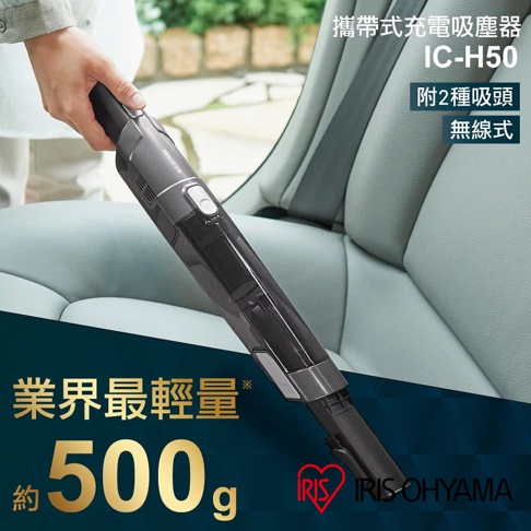 手持灰色與透明材質的攜帶式充電吸塵器 IC-H50，正被一隻手握著，置於汽車座椅上。
