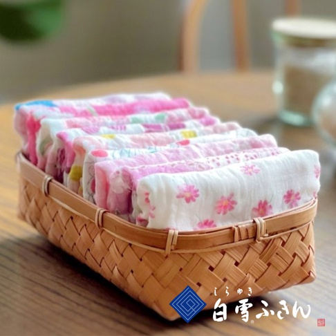 一籃竹編織紋理的拭巾，呈現粉色、白色、藍色等多種友禪染花卉圖案，材質輕柔。