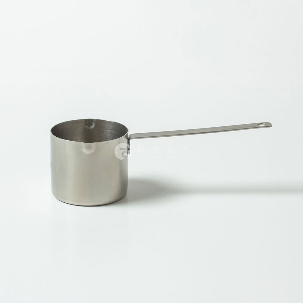 一個銀色不鏽鋼製成的長柄計量杯，杯身為圓柱形，帶有一個細長、平坦的把手，把手末端有一個掛孔。