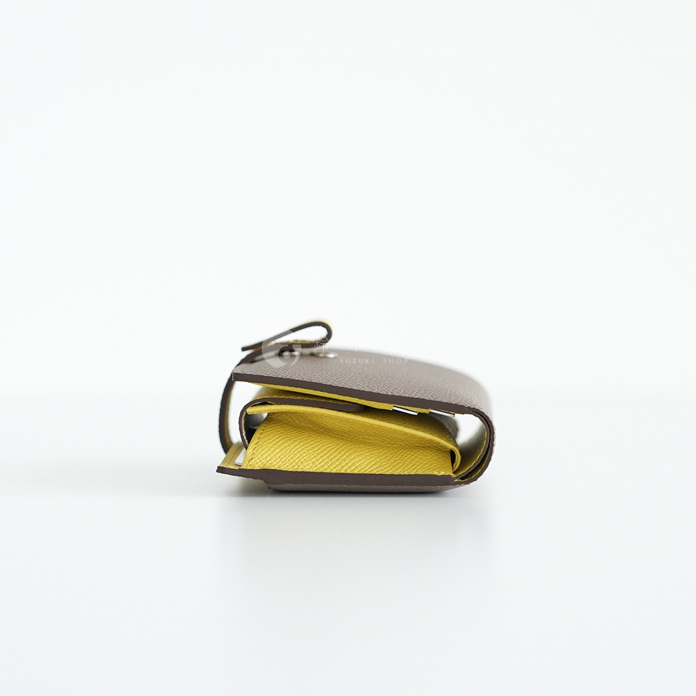 Atelier nuu noble皮革雙折短夾，近拍黃色內裡和棕色皮革外層，產品上有SUZUKI SHOP字樣。