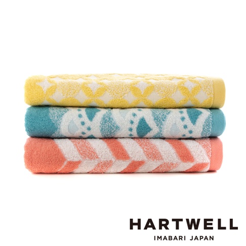 今治和風傳統紋樣言織浴巾，疊放展示。頂部為黃色浴巾，帶有白色菱形紋樣。中部為藍綠色浴巾，帶有白色幾何圖案。底部為珊瑚橘色浴巾，帶有白色箭頭紋樣。三條浴巾均為純棉材質，觸感柔軟。