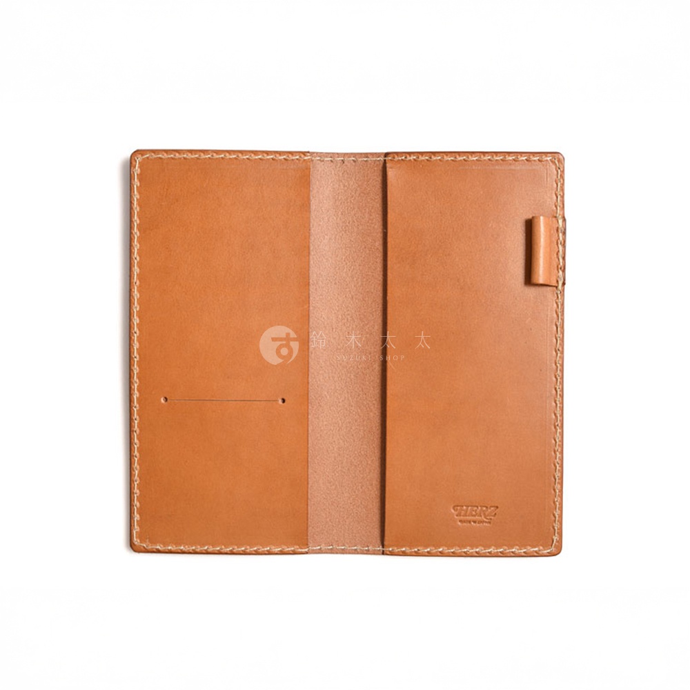 職人手作皮革輕便記事本書套，淺棕色，採用植物鞣革材質，內有兩格夾層，右側附有筆插，邊緣以縫線裝飾，右下角壓有「HERZ」品牌標誌。