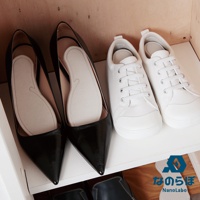 一雙黑色尖頭高跟鞋內放有淺米色珪藻土除濕墊，旁邊擺放一雙白色帆布鞋。