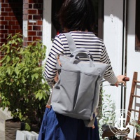 灰色高島帆布後背包，設有雙提把、拉鍊開口和前置口袋。