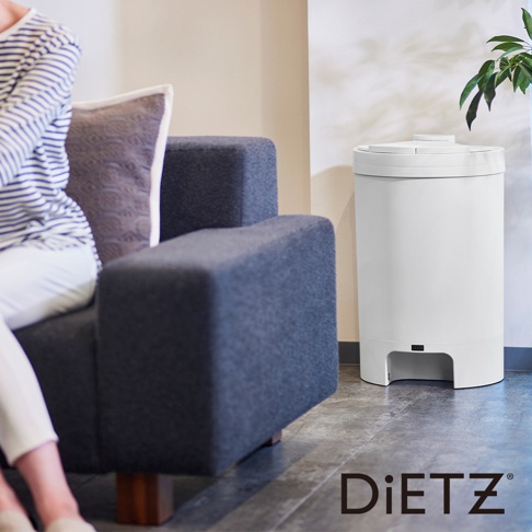 白色30公升自動感應靜音垃圾桶，圓柱形設計，頂部有圓形開蓋。垃圾桶前側下方有一個黑色感應開關。產品置於灰色沙發旁的地板上，背景為淺色牆壁，右側有綠色植物。