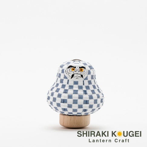 達摩不倒翁迷你提燈，白色紙質燈籠身印有藍色棋盤格紋，臉部描繪黑色眉毛、鬍鬚及橙色眼睛。提燈置於圓形木質底座上。