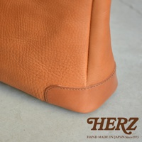 職人手作皮革Organ兩用商務托特包 G-61，此圖顯示包包的右下角，採用棕褐色紋理皮革與光滑皮革拼接，車縫線整齊，展現精緻工藝。