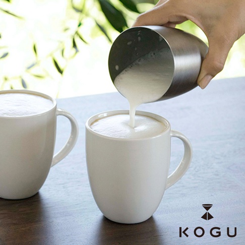 日製18-8不鏽鋼雪克杯傾倒奶泡至白色馬克杯中，杯中已有豐富的奶泡。
