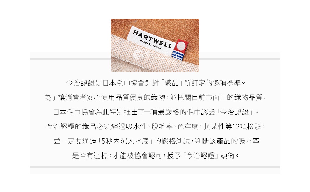 今治認證的迷你浴巾，特寫標籤，標籤上印有「HARTWELL IMABARI JAPAN」，浴巾為橘色調，材質為柔軟的棉質。