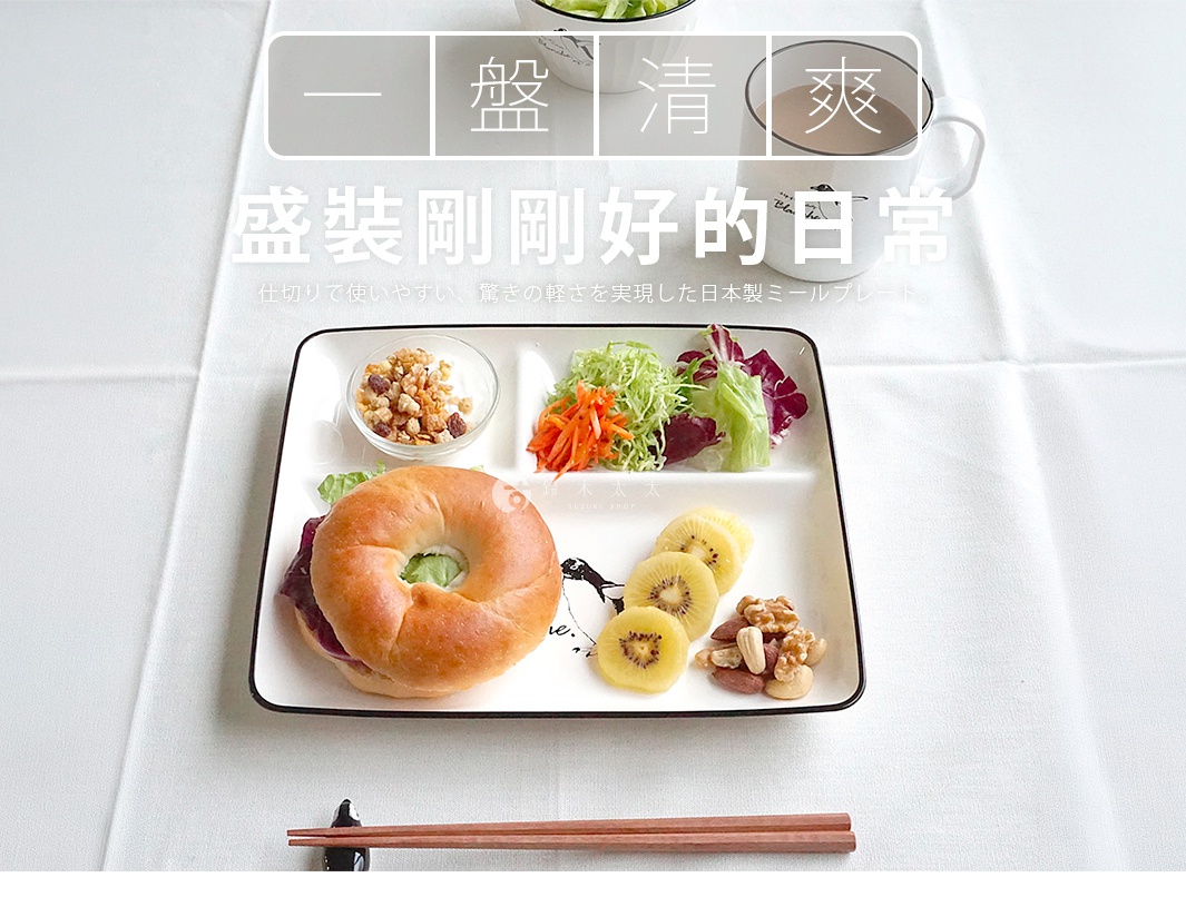 一張白色桌面上擺放著一個印有可愛企鵝插畫的 PADOU Blanche 輕量分隔餐盤，盤內整齊盛裝著貝果三明治、新鮮生菜沙拉、奇異果切片、堅果以及一小碗穀物優格，上方背景處有馬克杯與餐具，整體呈現出清新精緻的日常早餐擺盤氛圍。