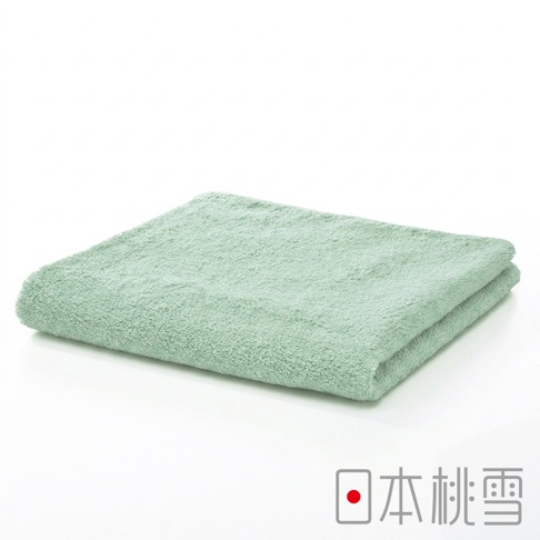這是一條摺疊整齊的日本桃雪精梳棉飯店毛巾，呈現清爽的淺綠色調，毛圈細緻豐厚，右下角印有日本桃雪品牌標誌。
