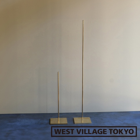 兩個黃銅製的一輪花器/燈具展示架，一個較高，一個較矮，皆有方形底座，立於藍色地面與淺色牆壁前。