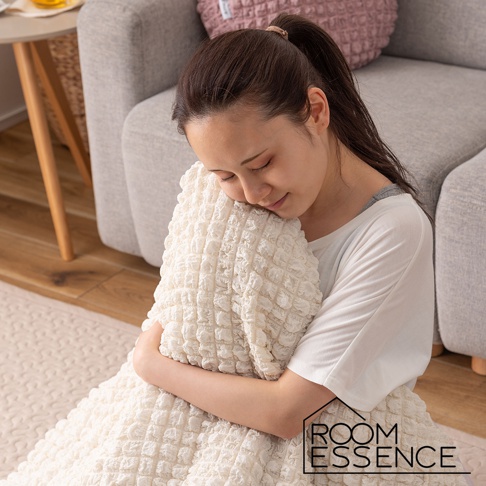 一位女性抱著一個乳白色、表面有立體方格紋路的涼感夾心包覆圓墊。