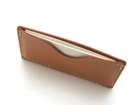 淺棕色皮革製成的職人手作卡片夾，以米白色縫線手工縫製，夾內裝有白色卡片，產品背景為白色。