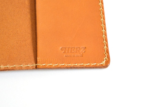 職人手作皮革厚革書套，淺棕色，紋理清晰，邊緣以明線縫合，內側壓印有「HERZ」及「MADE IN JAPAN」字樣。