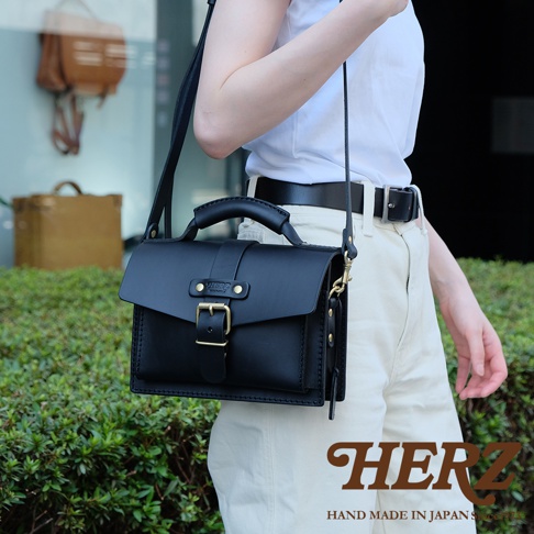 黑色皮革迷你單肩包，附有頂部提把、可調式肩帶及金色釦環。