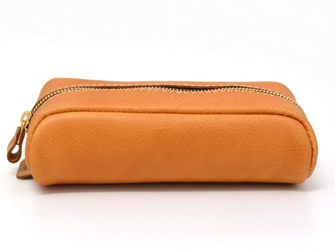 職人手作皮革圓角收納筆袋 (KP-1)，採用天然皮革材質，呈現溫潤的淺棕色調，表面有細緻的皮革紋理。筆袋為長條形，兩側圓潤，設有黃銅色拉鍊及皮革拉環，整體設計簡約實用。