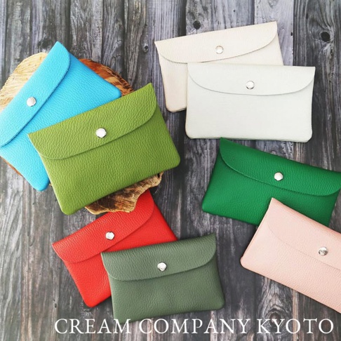 多個顏色、皮革紋理的京都職人手作多功能收納包，包括藍色、綠色、紅色、粉色和白色，皆配有銀色按扣，散佈在木紋背景上。