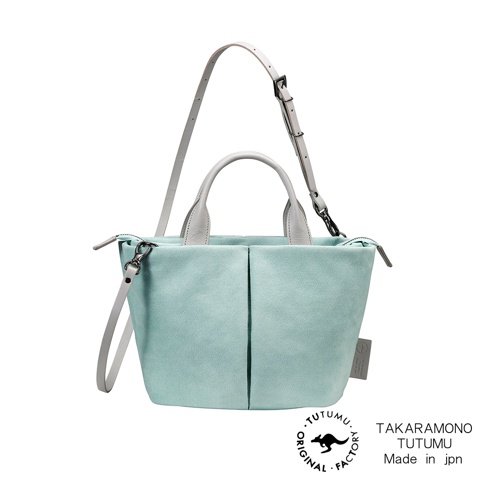 TUTUMU 品牌淺綠色麂皮材質的兩用手提斜背包，附有可拆卸的淺灰色皮革背帶和提把，印有品牌標誌及日文產地說明。