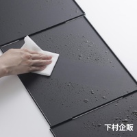 深灰色ㄇ型折疊防汙擋油板，表面有水珠，一隻手正用白色抹布擦拭。