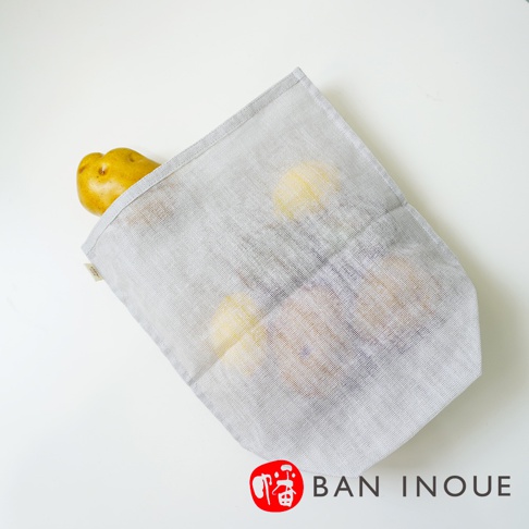 灰色蚊帳布收納袋，可見透氣網孔，袋內裝有數顆黃色馬鈴薯，袋口有品牌標籤。