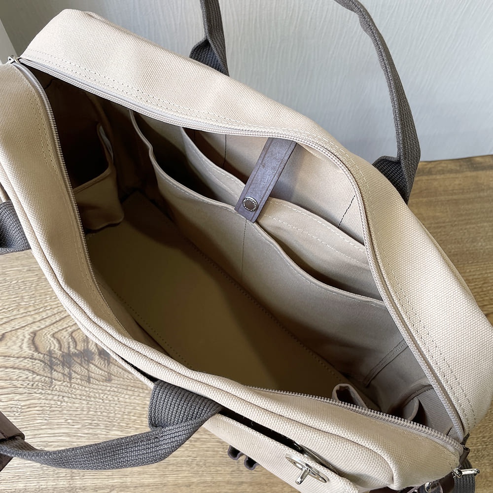 犬印純綿帆布商務公事包，米白色帆布材質，打開內裡，可見多層隔間與收納袋，搭配深灰色帆布提把。