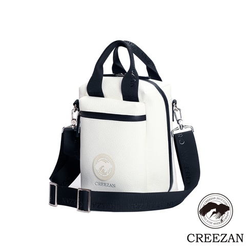 白色荔枝紋皮革方形側背包，帶有黑色飾邊、拉鍊和可調節肩帶，正面有品牌圓形標誌。