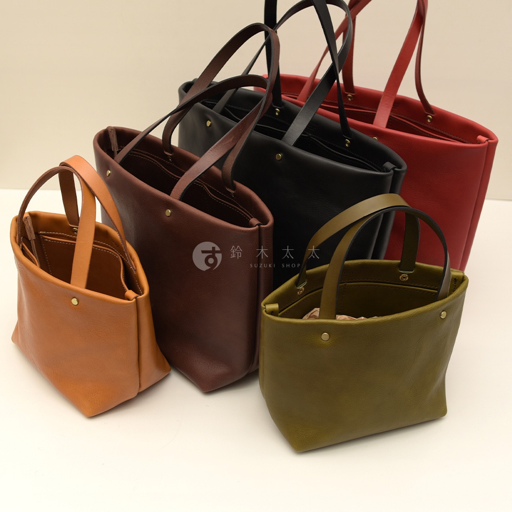 展示五個職人手作皮革托特包，顏色包含棕褐色、紅棕色、黑色、紅色及橄欖綠。包款為極簡設計，皆為開放式開口，配有兩條短提把，部分包款內可見口袋。