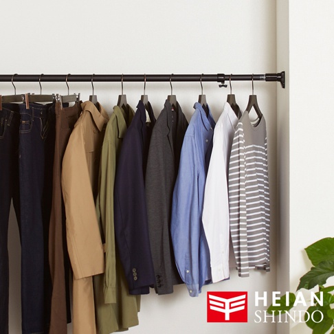 黑色金屬伸縮置物架上掛有深藍色牛仔褲、卡其色風衣、軍綠色長袖衫、深藍色西裝外套、灰色西裝外套、淺藍色襯衫、白色長袖襯衫和灰色條紋長袖衫。