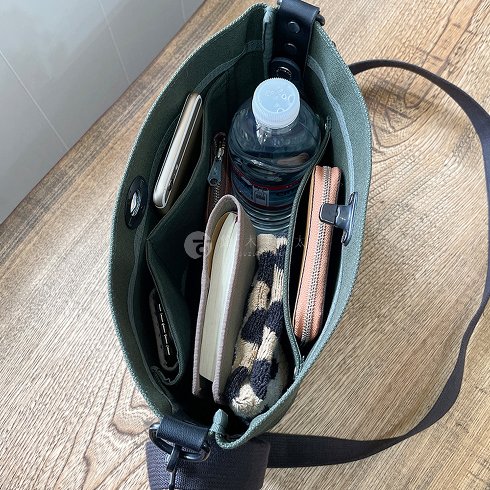 綠色純綿帆布迷你側背包，內部裝有手機、水瓶、筆記本、錢包和毛線配件。