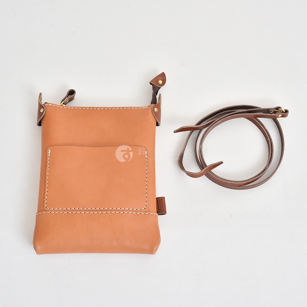 職人手作皮革直式隨身單肩包，淺棕色皮革，具備縫線細節，前方設有貼袋，附可調節式深棕色皮革背帶。