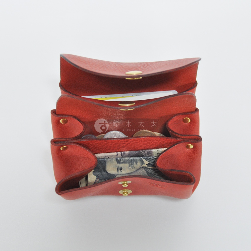 紅色皮革三層收納零錢包，內部裝有日圓紙鈔和硬幣，包體以金屬釘釦固定。