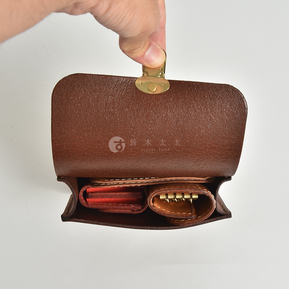 職人手作皮革經典腰包 E-1，展示深棕色皮革材質，內部收納著卡夾和鑰匙圈，整體風格簡約復古。