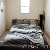 抗菌短絨舒柔雙人毯，採用漸層染設計，以淺綠、灰白為主色調，鋪蓋在木製雙人床上。