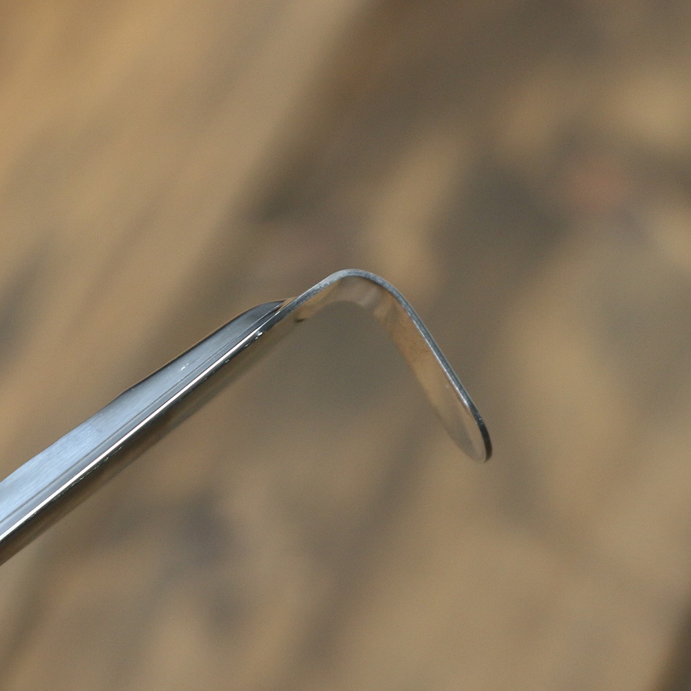 不鏽鋼中型撈勺的側面特寫，顯示銀色金屬材質，勺柄部分彎曲，邊緣光滑。