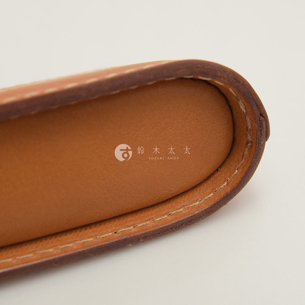 職人手作皮革三角弧形收納筆袋，近拍展示焦糖棕色皮革材質、車縫線細節，以及產品的弧形收納輪廓。