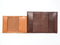 職人手作皮革翻蓋記事本書套，左邊為淺棕色皮革，右邊為深棕色皮革，兩者皆為可放入筆記本的內頁設計，有著簡潔的翻蓋式外觀。