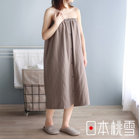 一位女性穿著一件淺棕色的棉紗混紡平口鬆緊浴巾裙，裙子上有灰色的鈕扣。