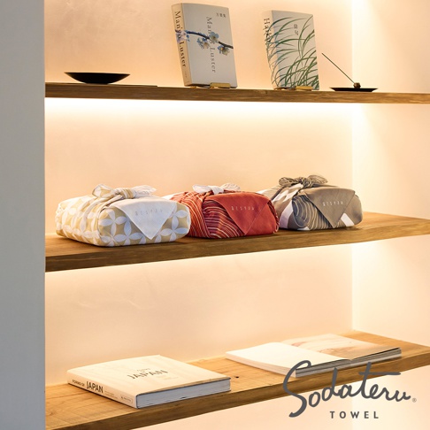 架子上擺放著書籍、香、包裝好的毛巾和一本名為 Sodateru TOWEL 的書。